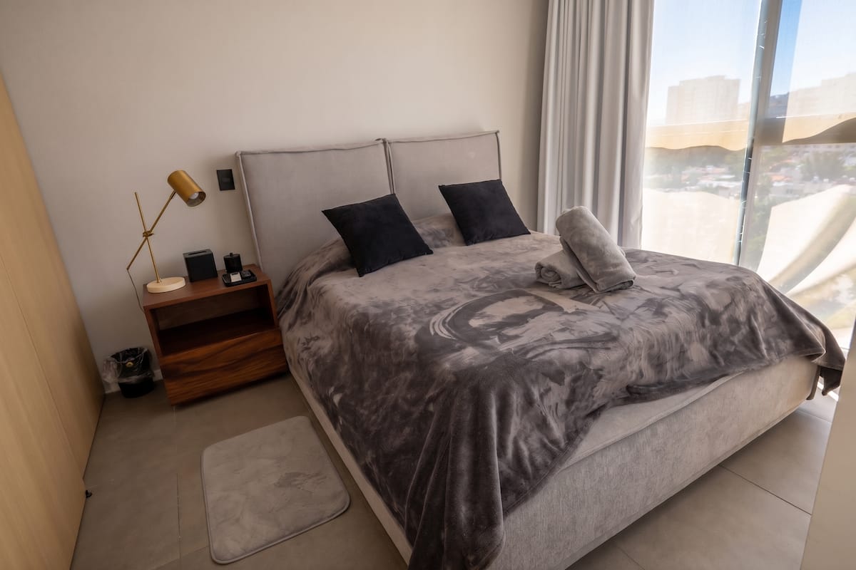 Habitación con cama matrimonial y luz natural lateral.