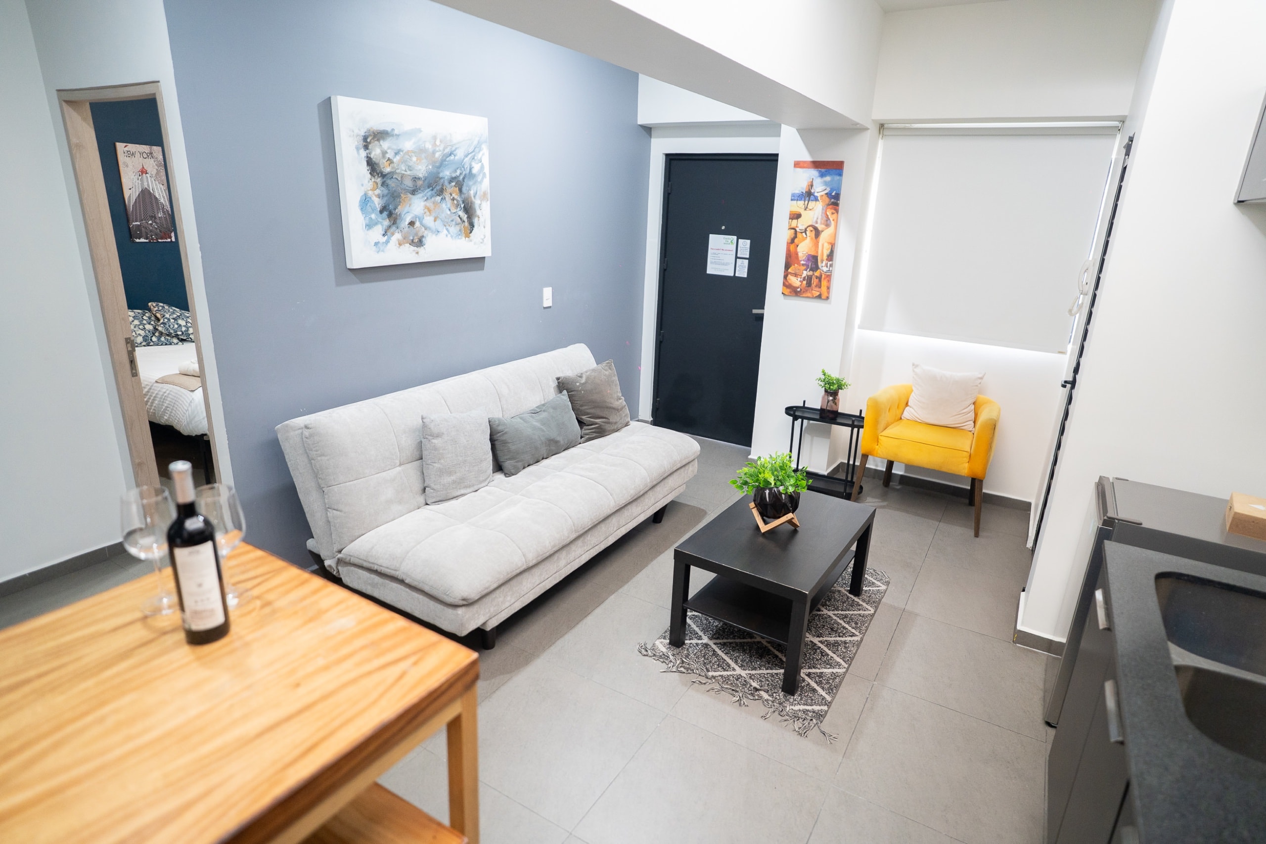 Sala con sofá, sillón amarillo y mesa comedor.