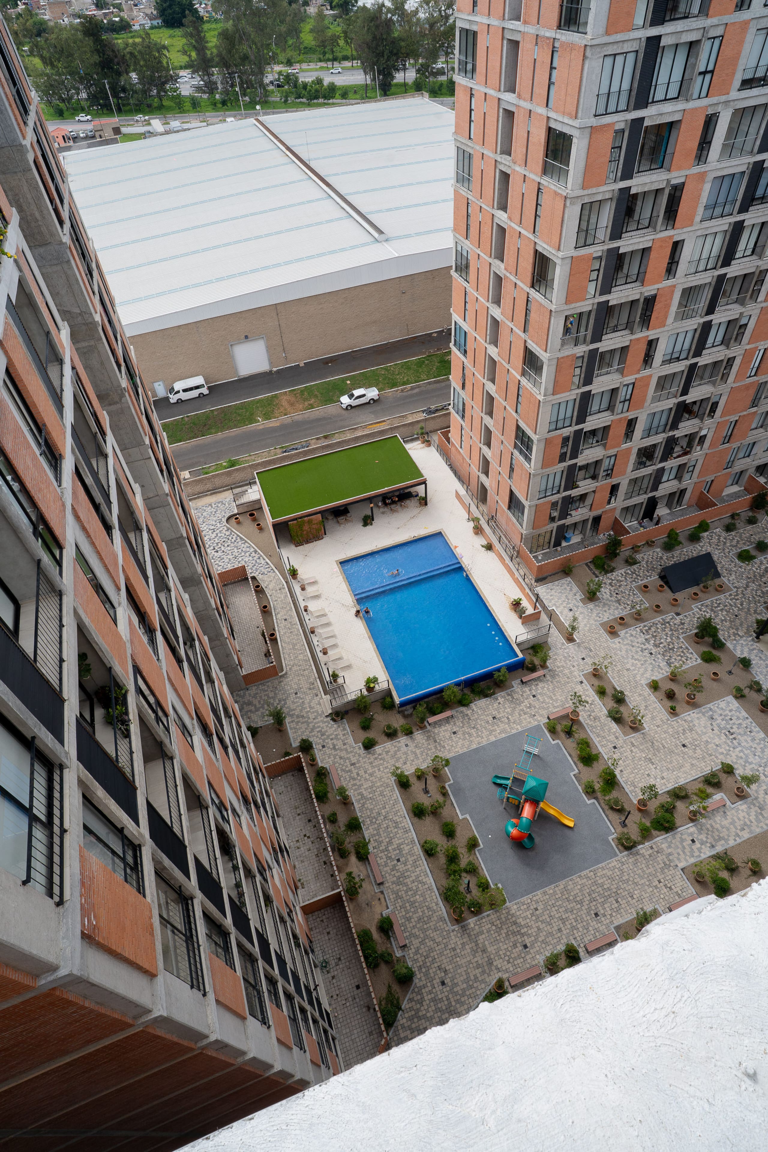 Vista aérea de alberca, juegos infantiles y edificios.