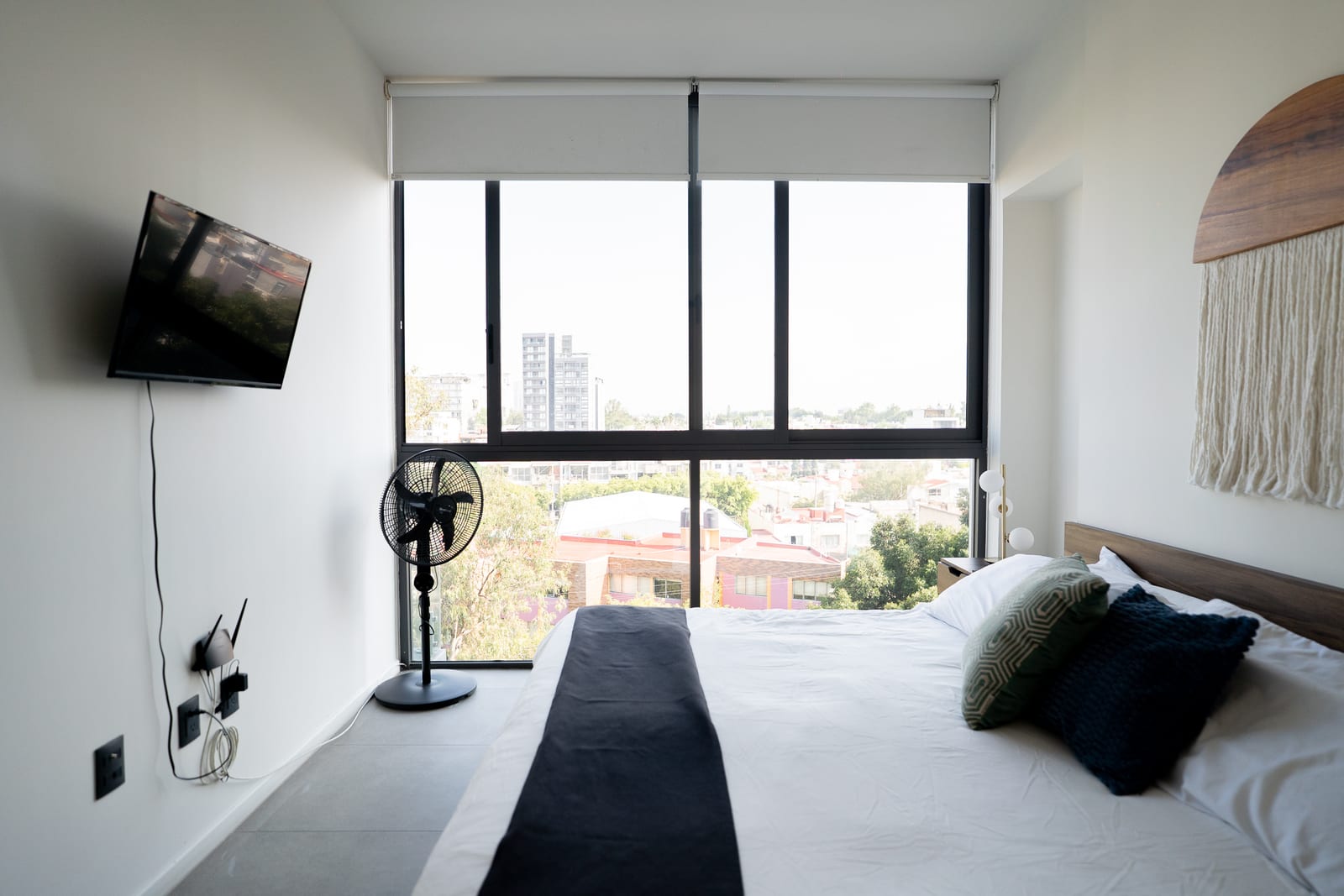 Cama matrimonial frente a televisión y gran ventana