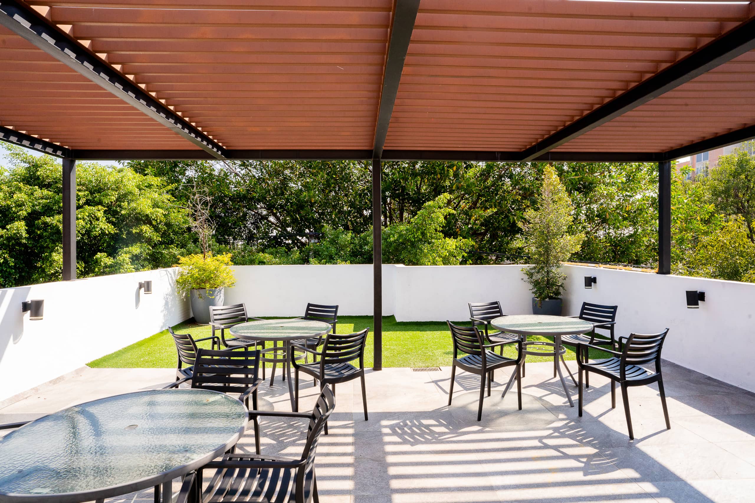 Terraza común con mesas bajo una pérgola