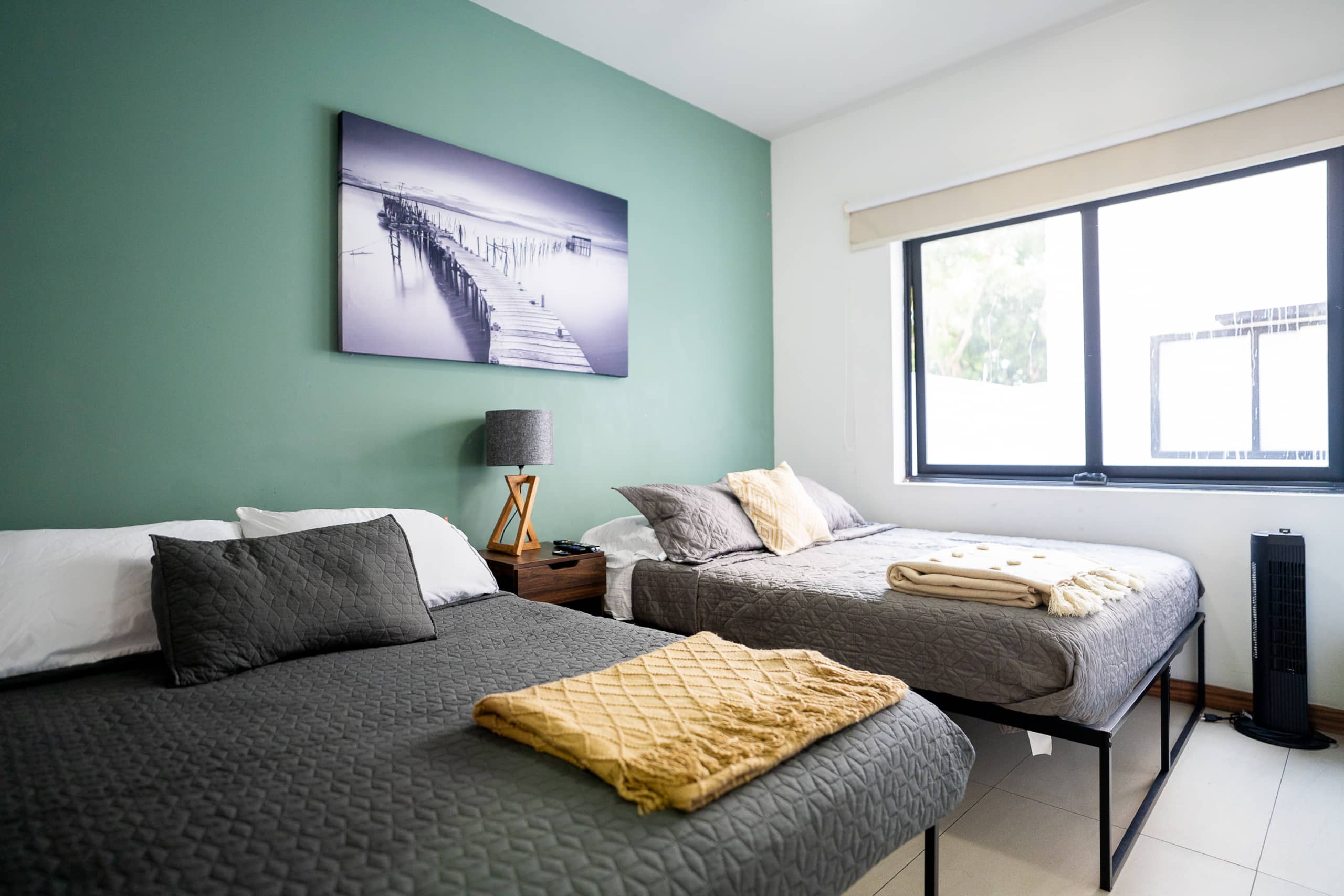 Recámara con dos camas y pared verde