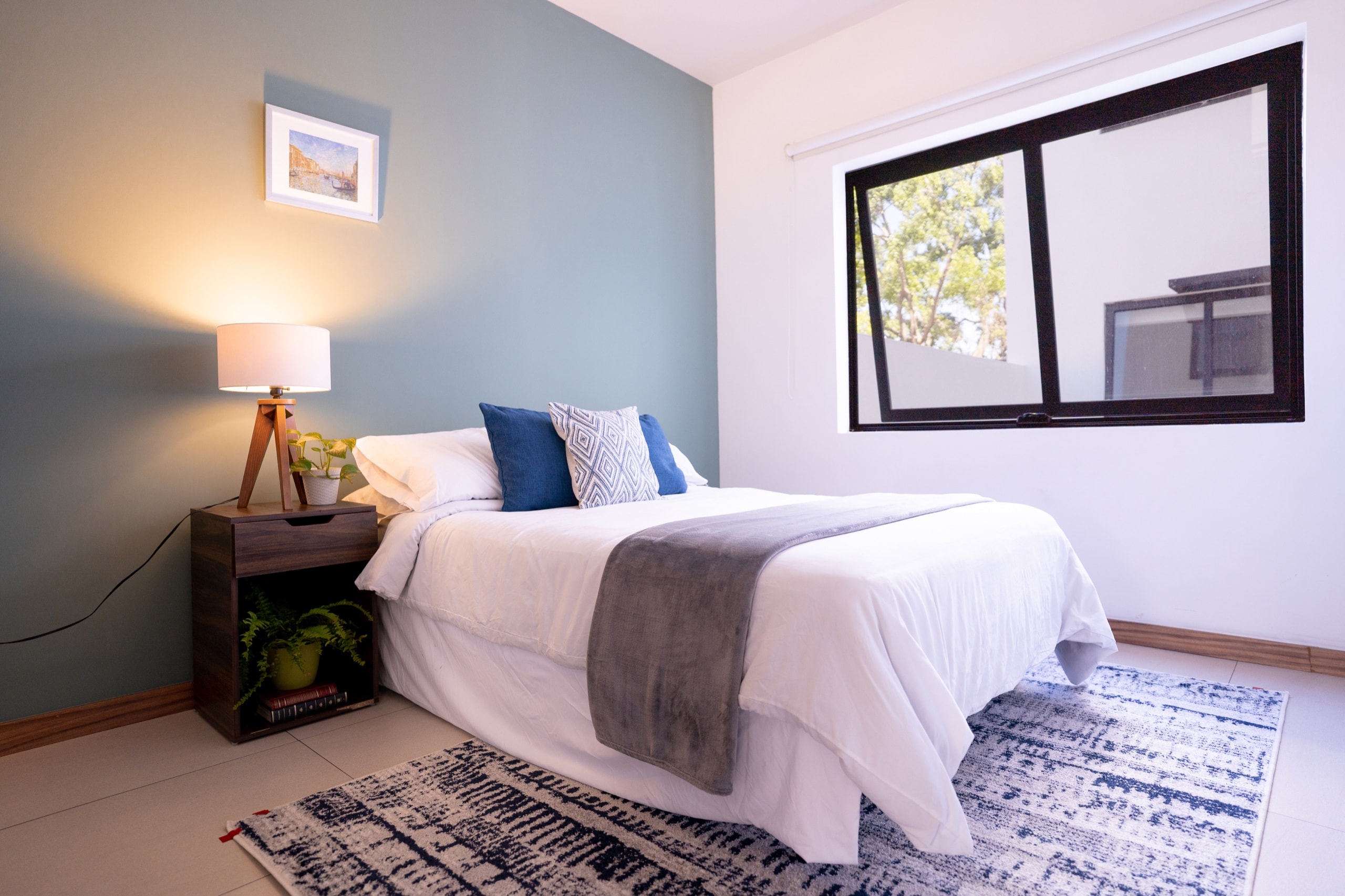 Cama matrimonial con sábanas blancas y ventana abierta