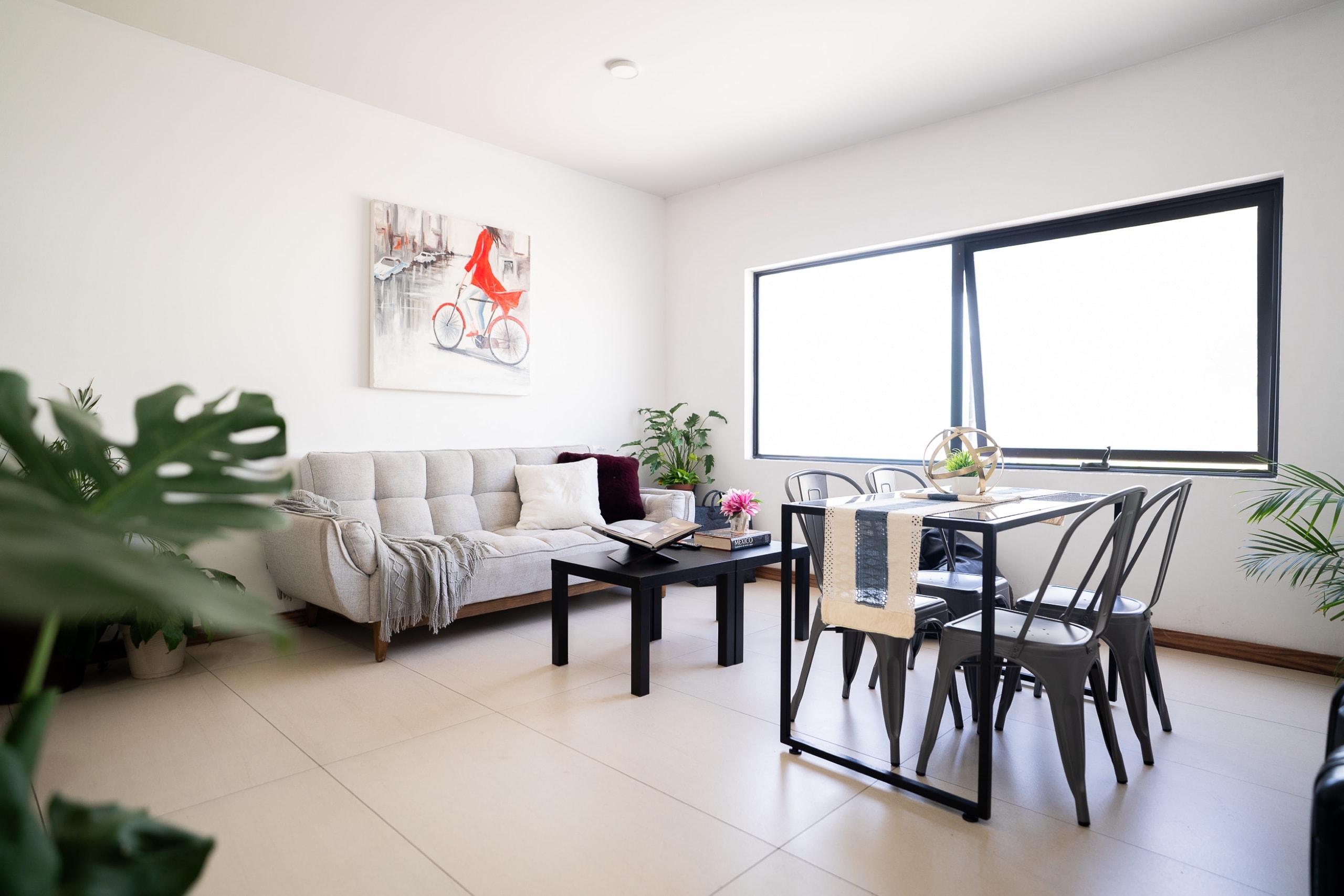 Sala comedor con sofá, mesa y gran ventanal.