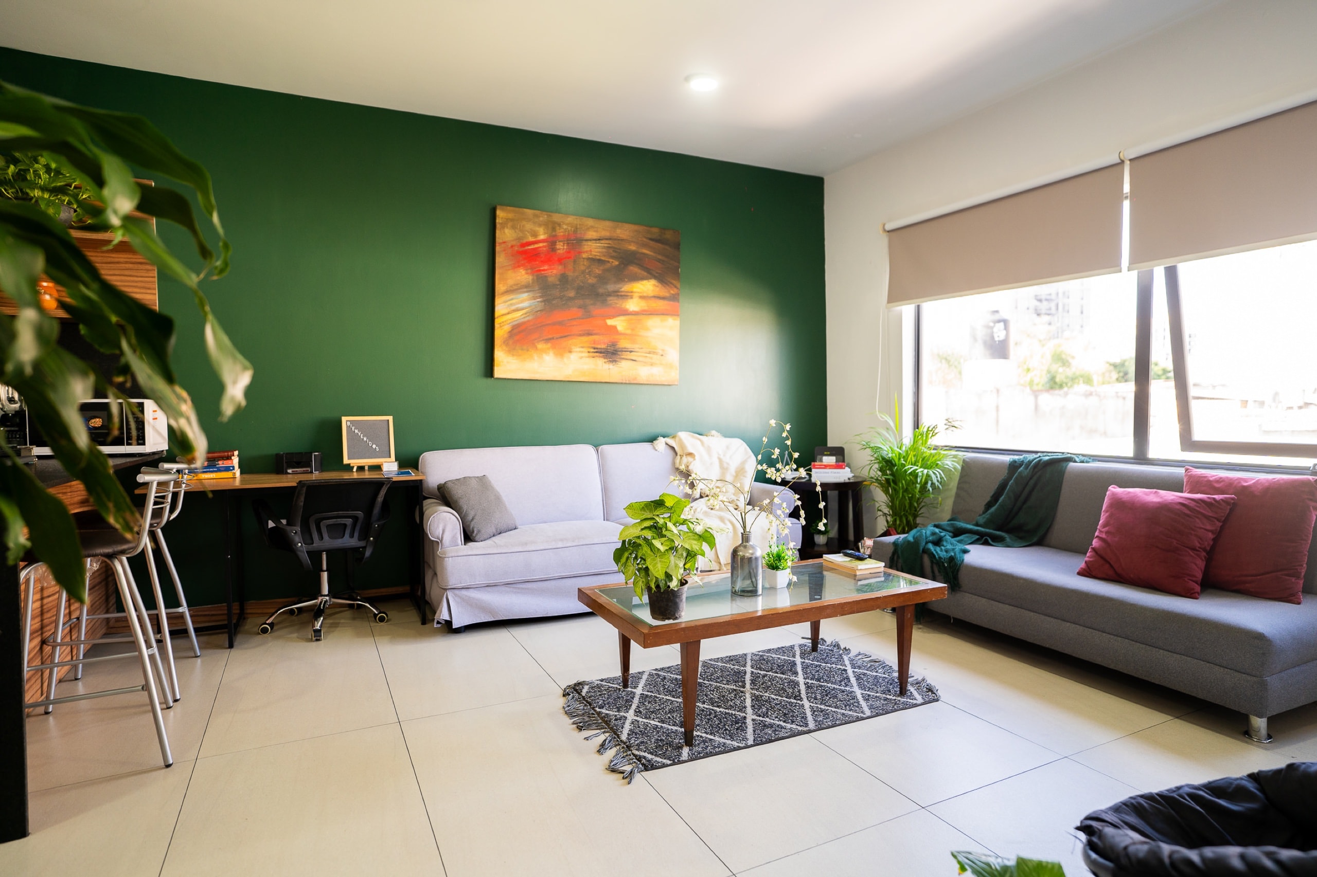 Sala con sofás, escritorio y pared verde.